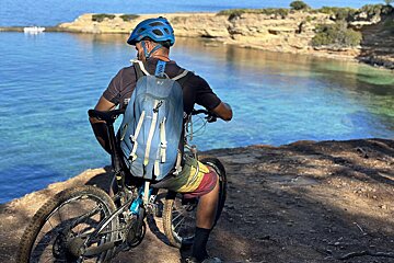 A man on a bike with a backpack that says ' shimano ' on it