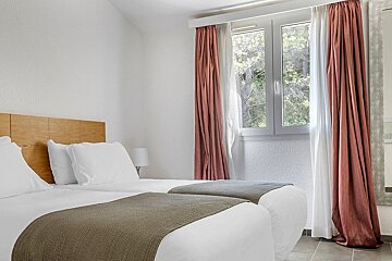 A hotel room with two beds and a window