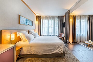 A hotel room with a large bed and a chair