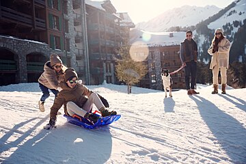A group of people playing in the snow with a dog