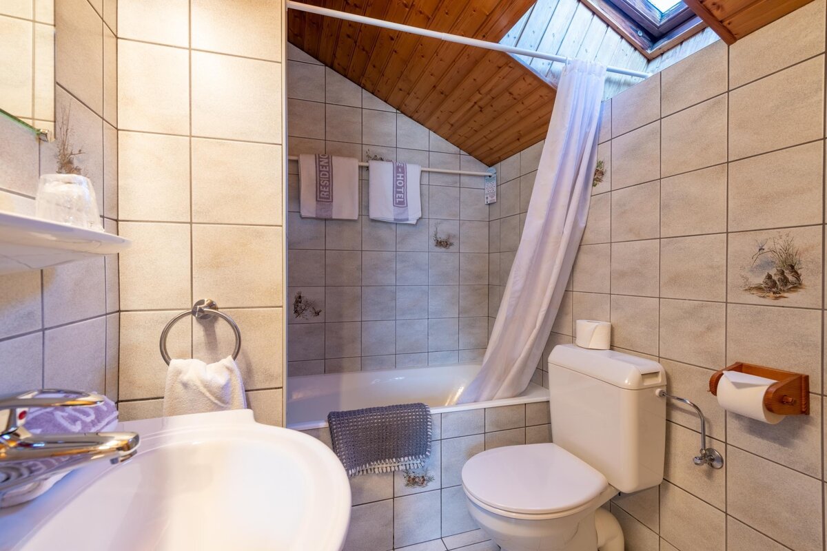 A bathroom with a toilet a sink and two towels that say hotel