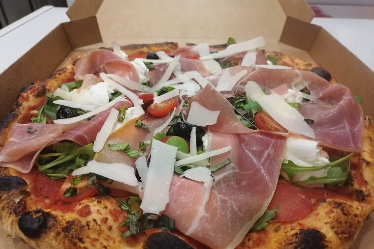 A pizza with meat and vegetables in a cardboard box