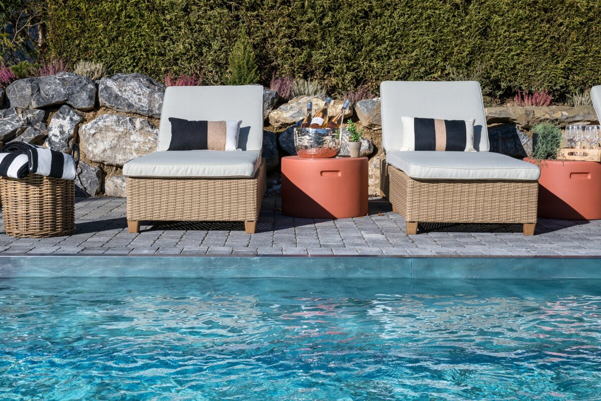 Two wicker chairs sit next to a swimming pool
