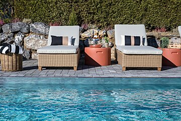 Two wicker chairs sit next to a swimming pool