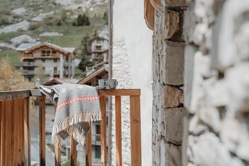 A balcony with a blanket and two mugs on it