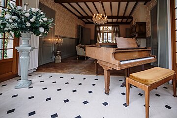 A piano sits in a room with a chandelier hanging from the ceiling