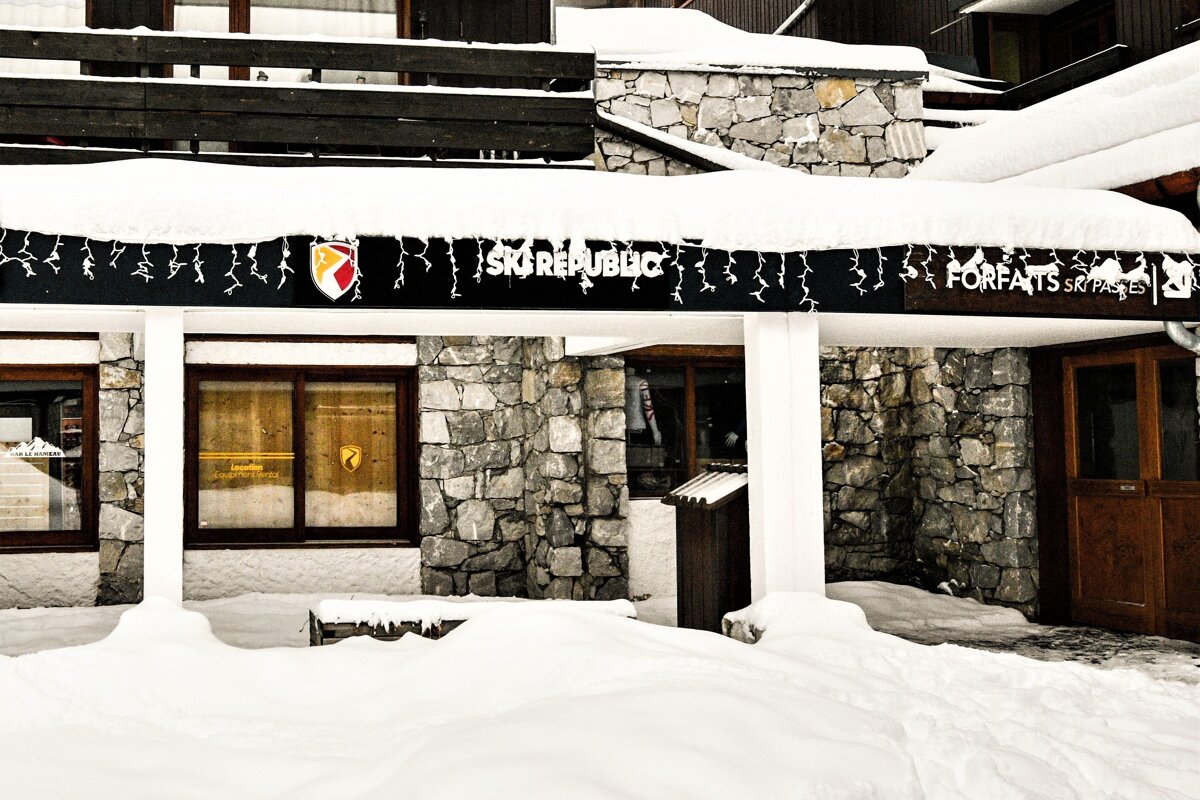 A snow-covered building with stone and wood architecture features a 