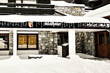 A snow-covered building with stone and wood architecture features a 