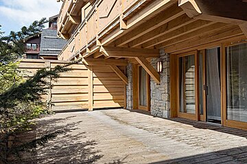 A wooden deck with sliding glass doors and a stone wall