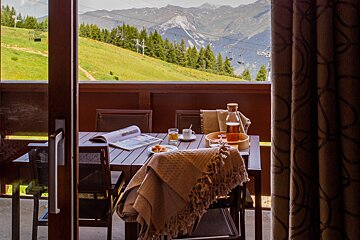 A balcony with a table and chairs and a view of mountains