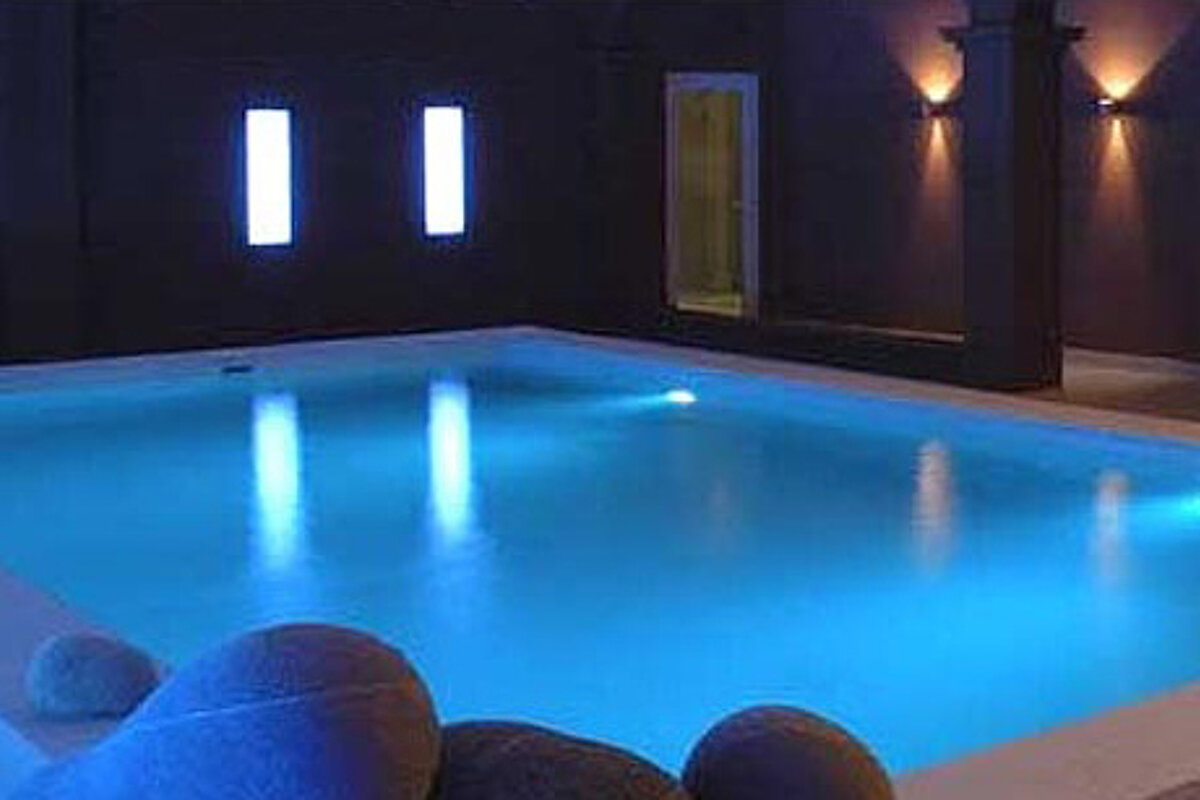 A swimming pool is lit up at night with blue lights