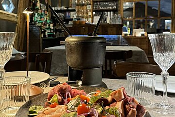 A fondue pot sits on a table next to a plate of food