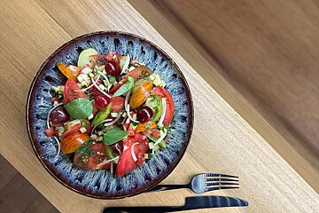 A salad with tomatoes and other vegetables on a blue plate