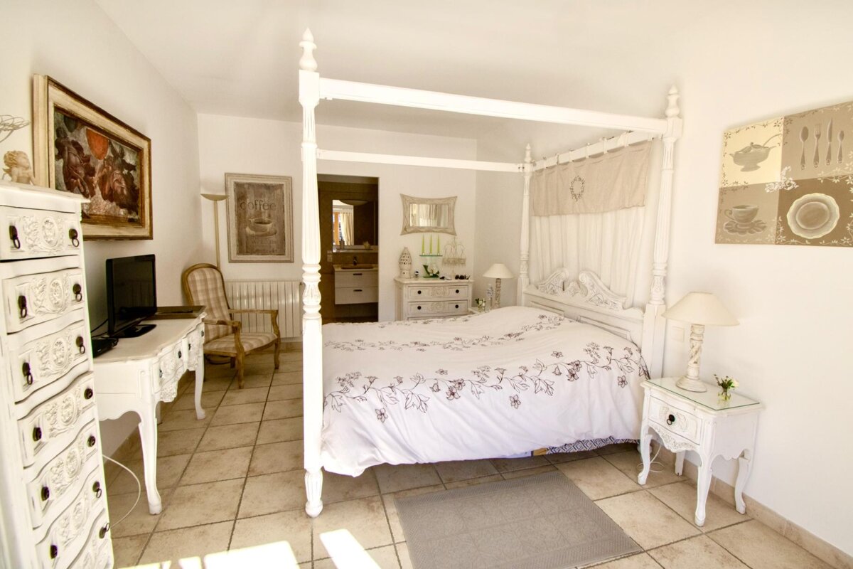 A bedroom with a four poster bed and a dresser