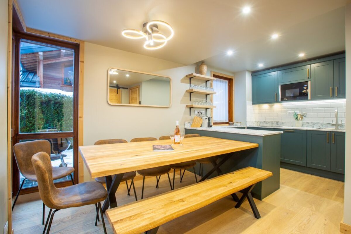 A kitchen with green cabinets and a wooden table