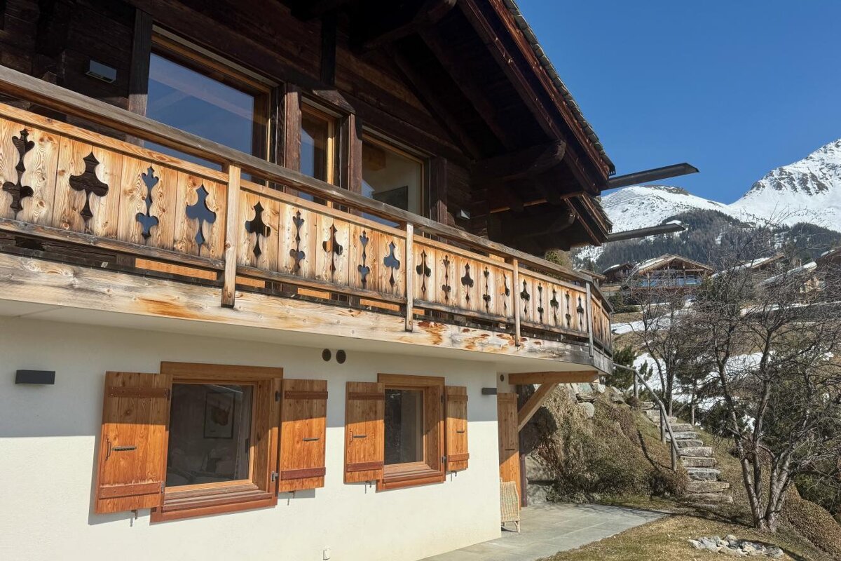A white house with a wooden railing and shutters