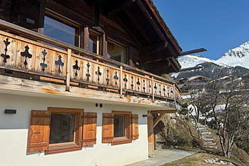 A white house with a wooden railing and shutters