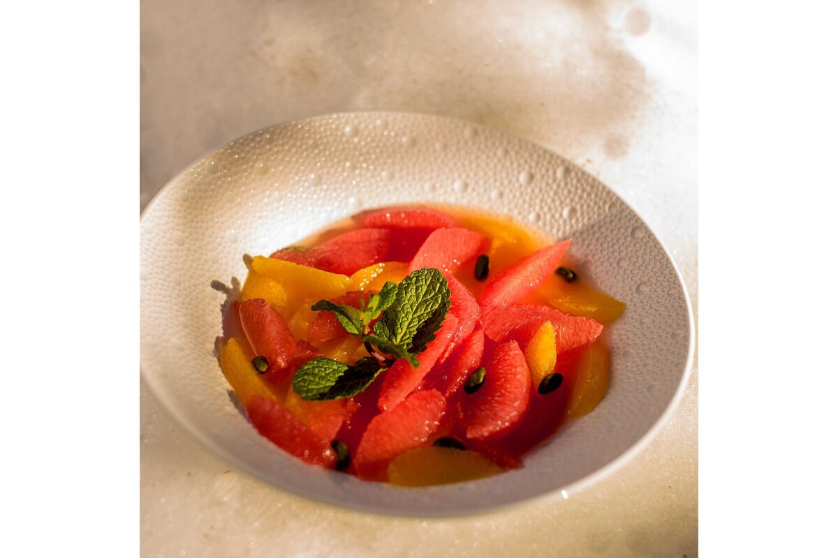 A white bowl filled with sliced fruit and mint leaves