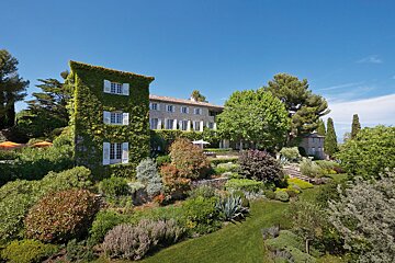 A large house is surrounded by a lush green garden