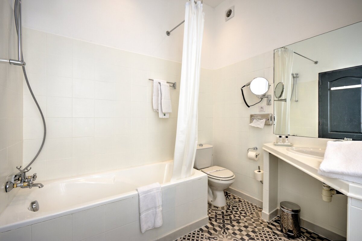 A bathroom with a bathtub toilet and mirror