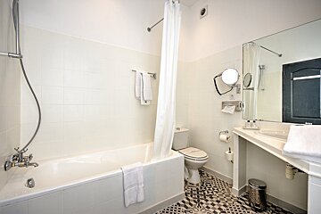 A bathroom with a bathtub toilet and mirror