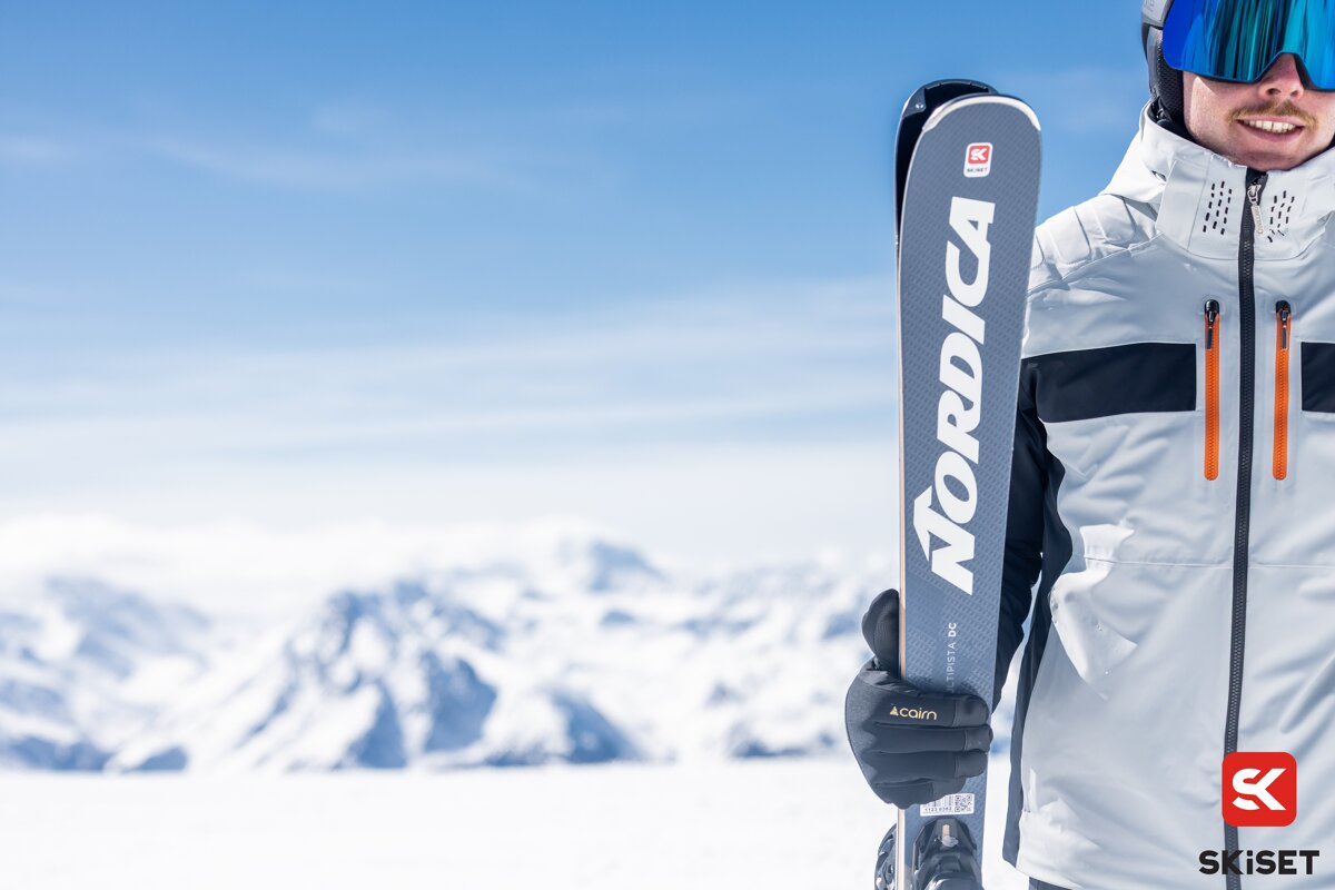 A person holding a pair of nordica skis