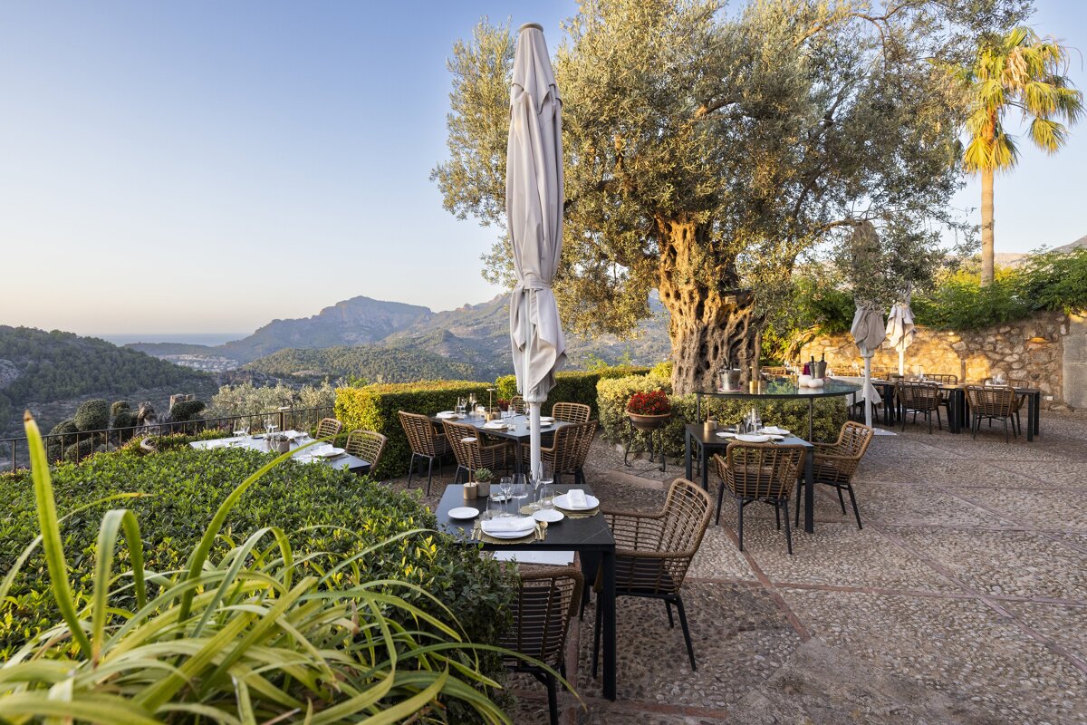 A patio with tables and chairs and an umbrella