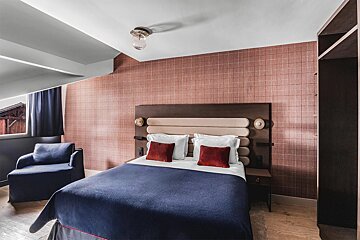 A hotel room with a bed and a chair