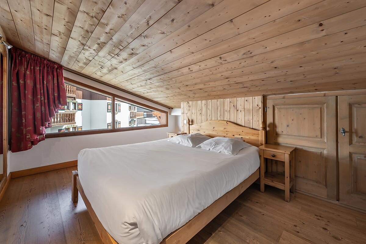 A bedroom with a wooden ceiling and a bed