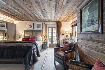 A bedroom with a bed and chairs and a painting on the wall