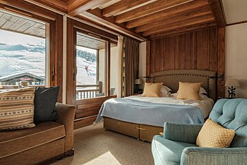 A bedroom with a bed and a chair with a view of a ski slope