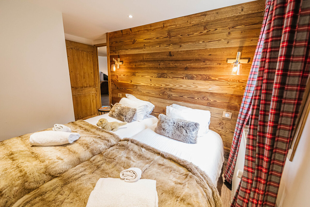 A bedroom with two beds and a wooden wall