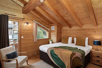 A bedroom with a bed and a chair in it