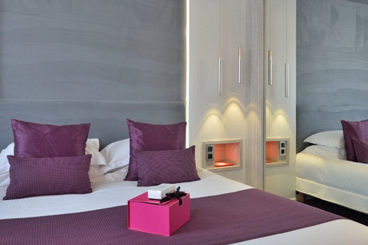 A bed with purple pillows and a pink box on it