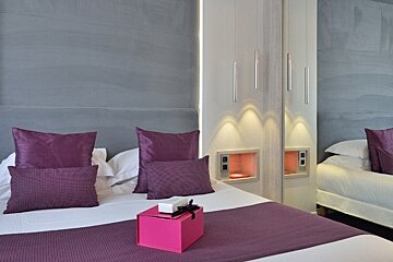 A bed with purple pillows and a pink box on it