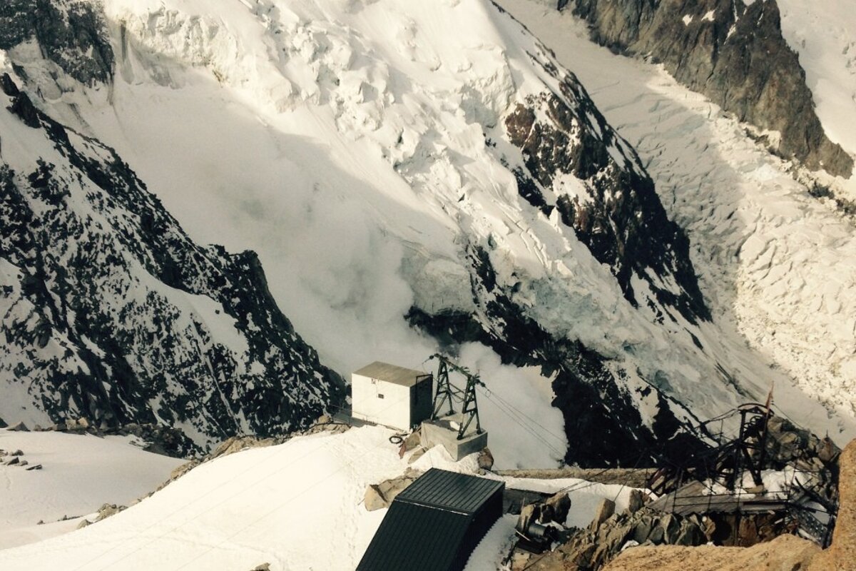 A snowy mountain with a black building in the foreground