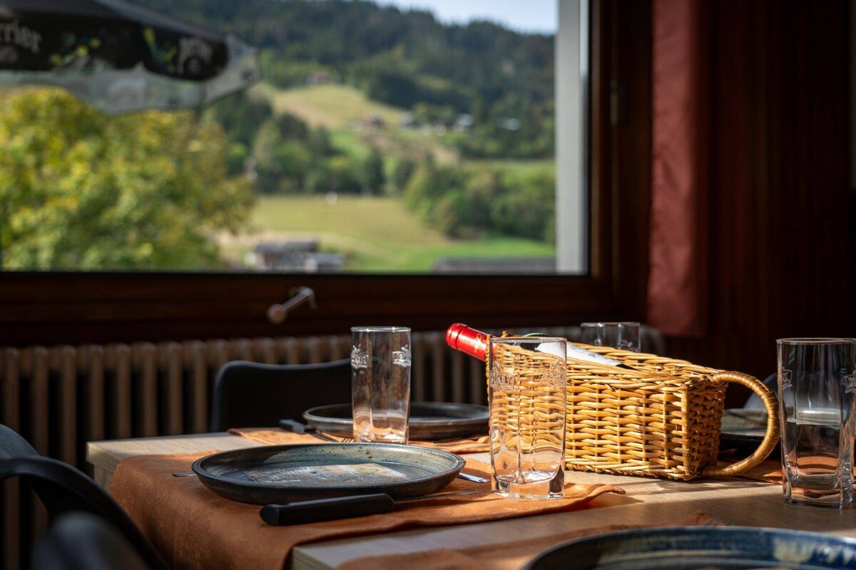 A bottle of wine sits in a wicker basket on a table