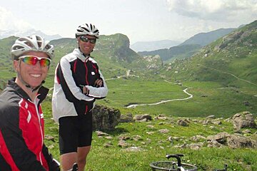 2 men in road cycling gear at the top of a pass