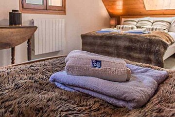 A bed with a fur blanket and towels on it in a bedroom