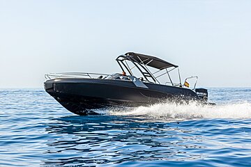 Sleek black motorboat cruising fast through blue water, kicking up white spray.