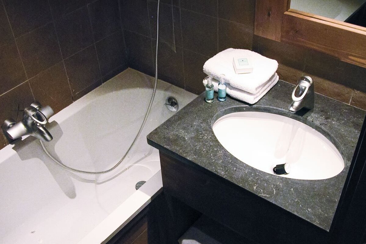 A bathroom with a bathtub and a sink with a soap that says ' a ' on it