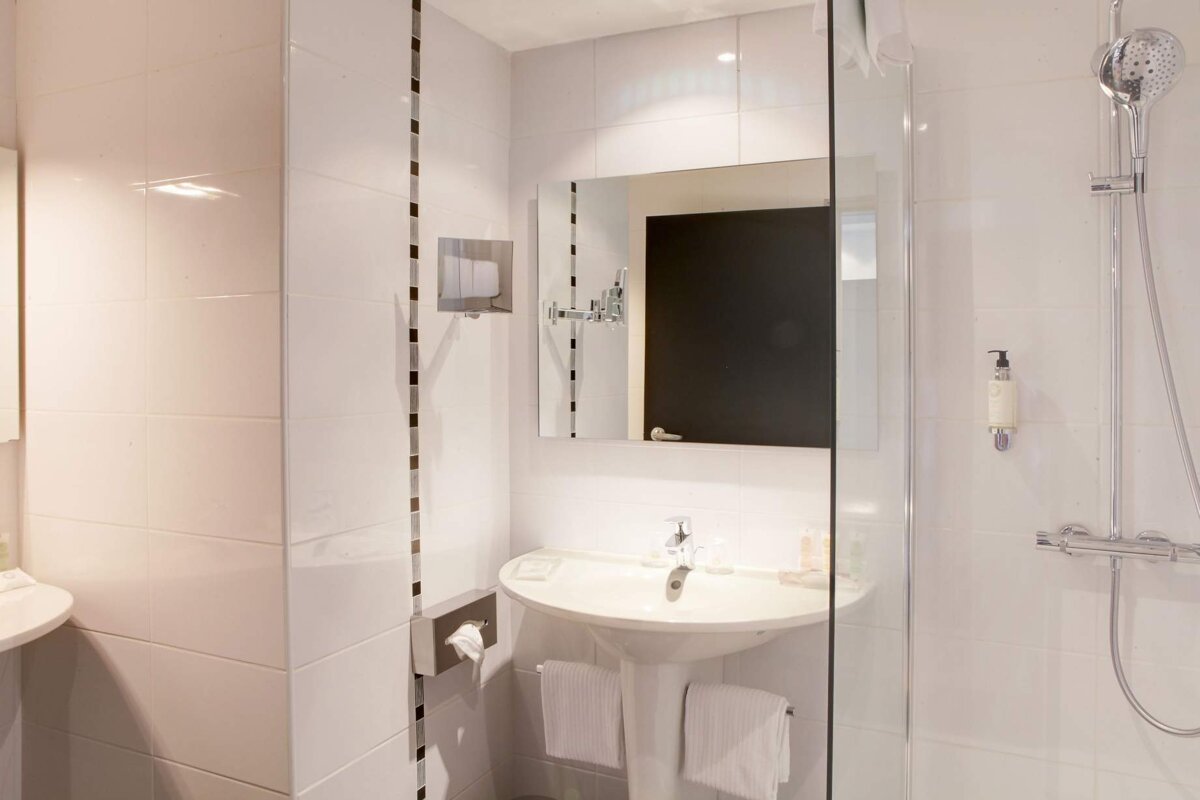 A bathroom with a sink a mirror and a shower