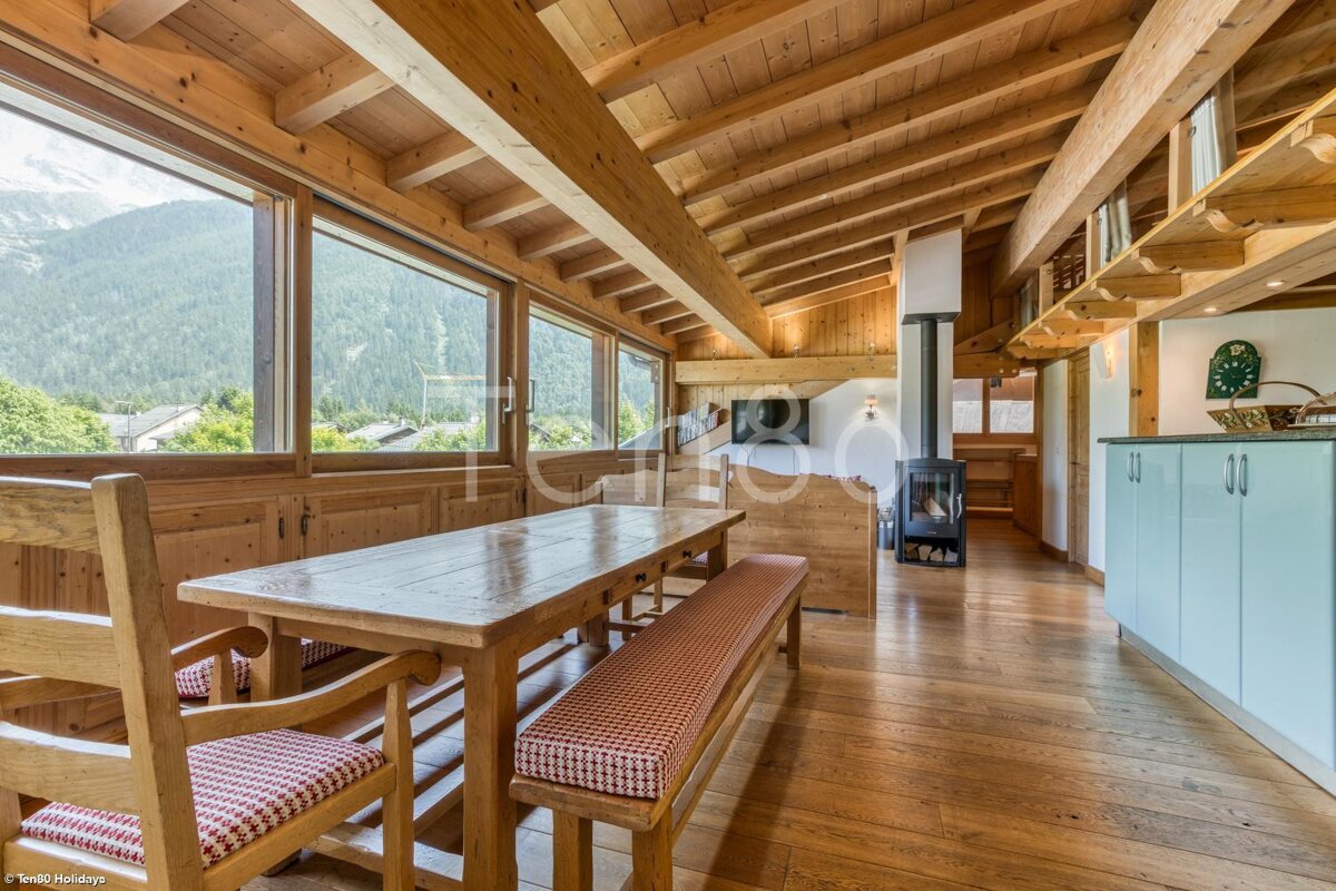 A wooden table with a bench sits in a room with a lot of windows