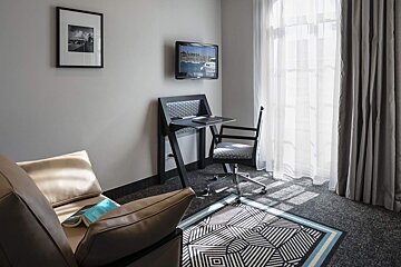 A room with a chair a desk and a flat screen tv