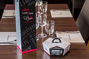 a table with a wine bag & take away box