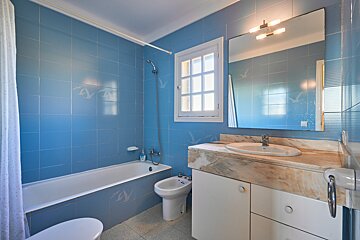 A bathroom with blue tiles and a sink and toilet