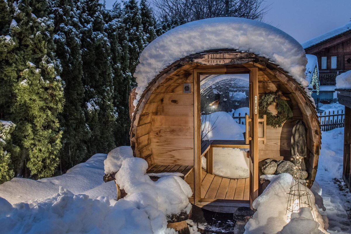 A wooden barrel covered in snow with a sign that says sauna