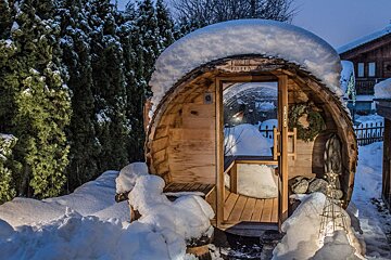 A wooden barrel covered in snow with a sign that says sauna