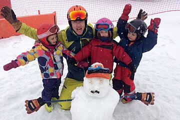 children with a ski guide & snowman