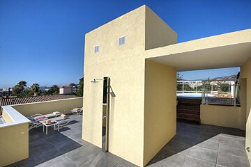 A rooftop area with a hot tub and a shower